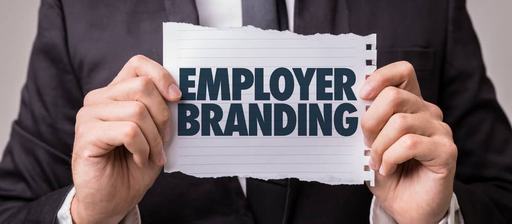 Manager hält Zettel mit dem Schirftzug "Employer Branding" | ACP - IT for innovators.